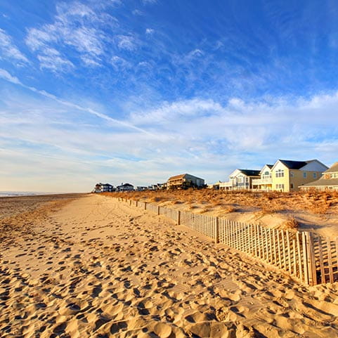 A sandy beach with colorful houses lining the shore under a clear blue sky