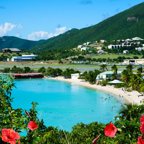 A serene lake surrounded by lush greenery and mountains, reflecting the clear blue sky above