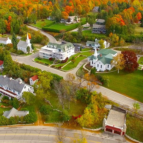 Aerial view of a small town nestled among trees and houses.