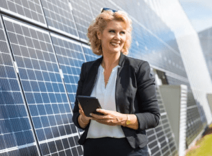 Woman standing by solar panels while looking at her tablet