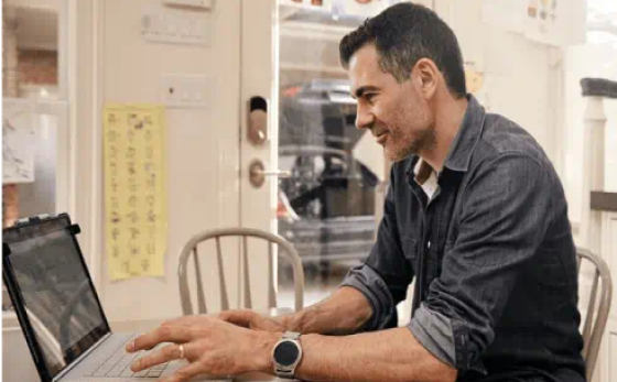 Man interacting with a laptop in his kitchen looking at Solar Loan Agreement