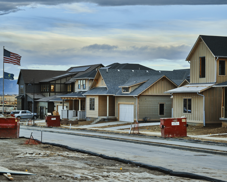 A street with houses under construction and an American flag waving in the wind.