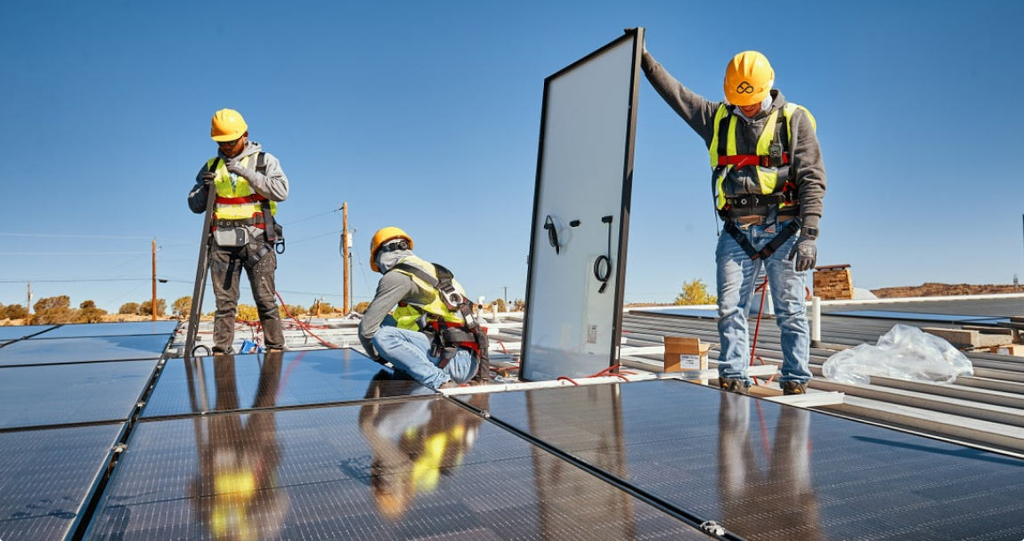 Three construction workers installing solar panels